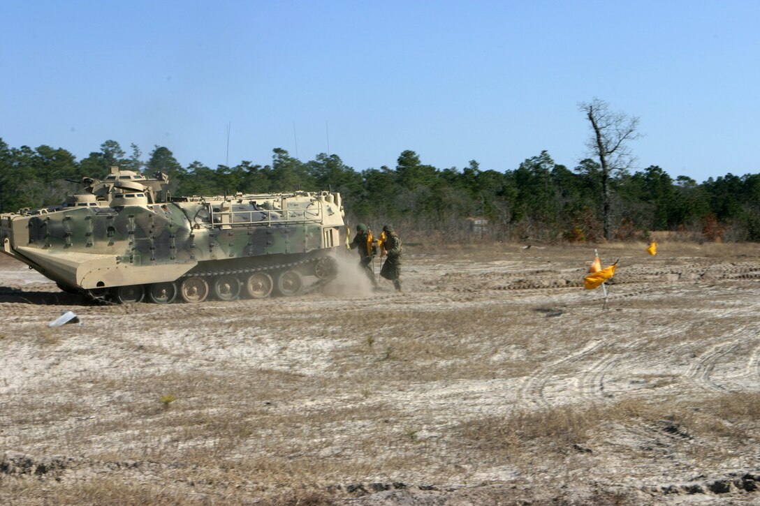 MAIRNE CORPS BASE CAMP LEJEUNE, N.C. (March 10, 2005) ? Two combat engineers from 2d Combat Engineer Battalion run behind a Amphibious Assault Vehicle putting up flags marking the safe lane through the mine field during a breaching exercise at Engineer Training Area 2 March 10.  The exercise lasted three days and included numerous training evolutions.