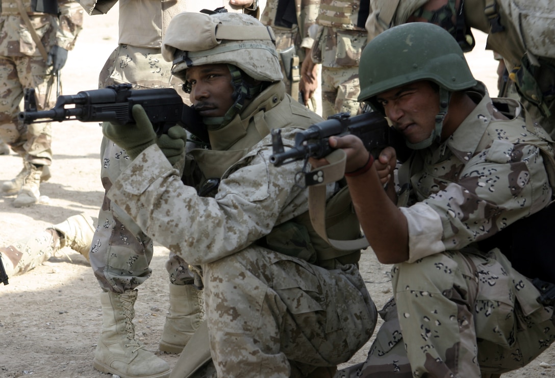 FALLUJAH, Iraq - Cpl. Nilton F. Ramos, course instructor from Company B, 1st Battalion, 6th Marine Regiment, aims his AK-47 alongside an Iraqi soldier to demonstrate proper technique.  1st Battalion, 6th Marine Regiment is helping Iraqi Security Forces conduct a "Lion Training" program to teach new Iraqi army recruits fundamentals of marksmanship, first aid in combat, and military customs and courtesies.
