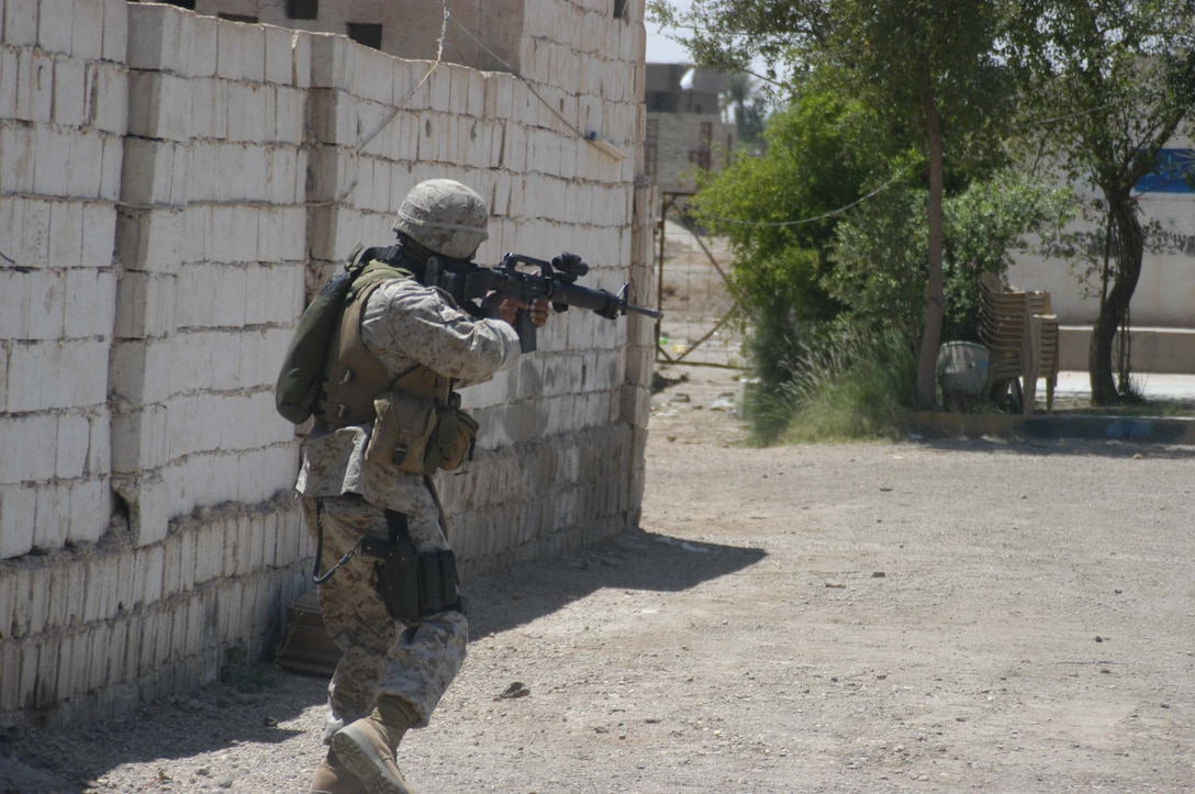 AR RAMADI, IRAQ (May 10, 2005) - With his weapon at the ready position, Sgt. Hector Martinez Jr., noncommissioned officer with Team 1, Detachment 3, 5th Civil Affairs Group, leads the way for his fellow civil affairs Marines so they can inspect minor property damage done to two businesses in the city here. The 28-year-old from Fontana, Calif., and his fellow civil affairs Marines conducted a detailed battle site assessment of two automotive shops that elements of 1st Battalion, 5th Marine Regiment, damaged during a recent cordon and search mission. Marines with 5th CAG will ensure the owners are properly compensated for the damages incurred to their establishments. Photo by Cpl. Tom Sloan