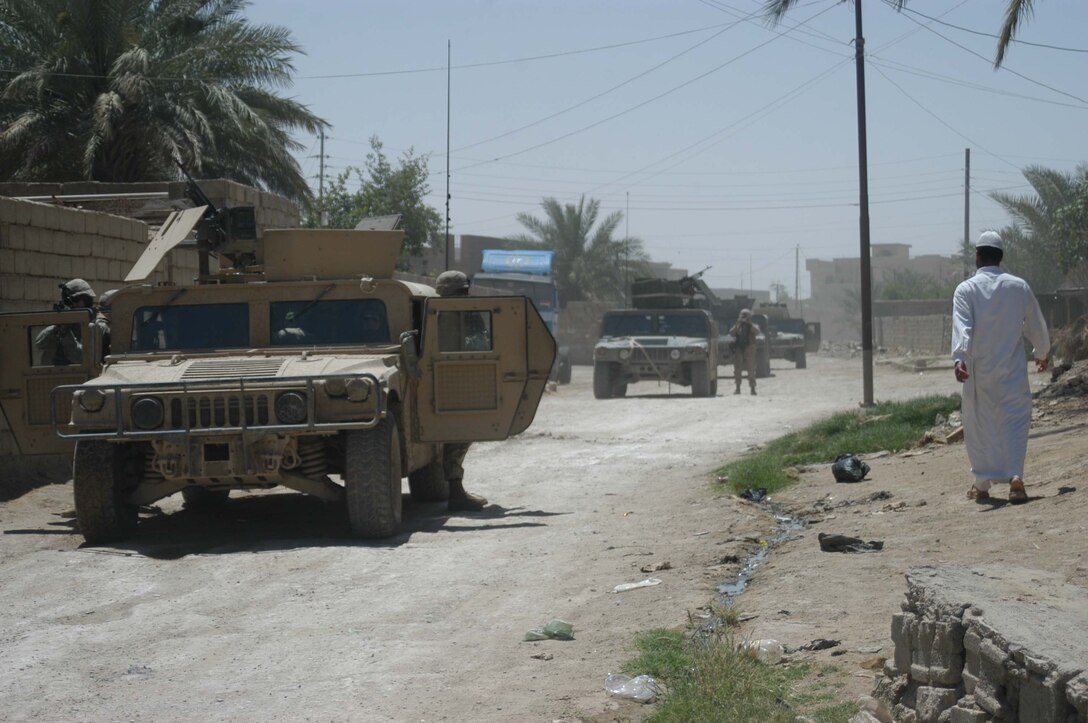 AR RAMADI, IRAQ (May 10, 2005) - An Iraqi man walks past Marines with Mobile 1, Company C, 1st Battalion, 5th Marine Regiment, while they secure a street here for Marines with Team 1, Detachment 3, 5th Civil Affairs Group. The civil affairs Marines conducted a detailed battle site assessment of two automotive shops that elements of 1st Battalion, 5th Marine Regiment, damaged during a recent cordon and search mission. Marines with 5th CAG will ensure the owners are properly compensated for the damages incurred to their establishments. Photo by Cpl. Tom Sloan