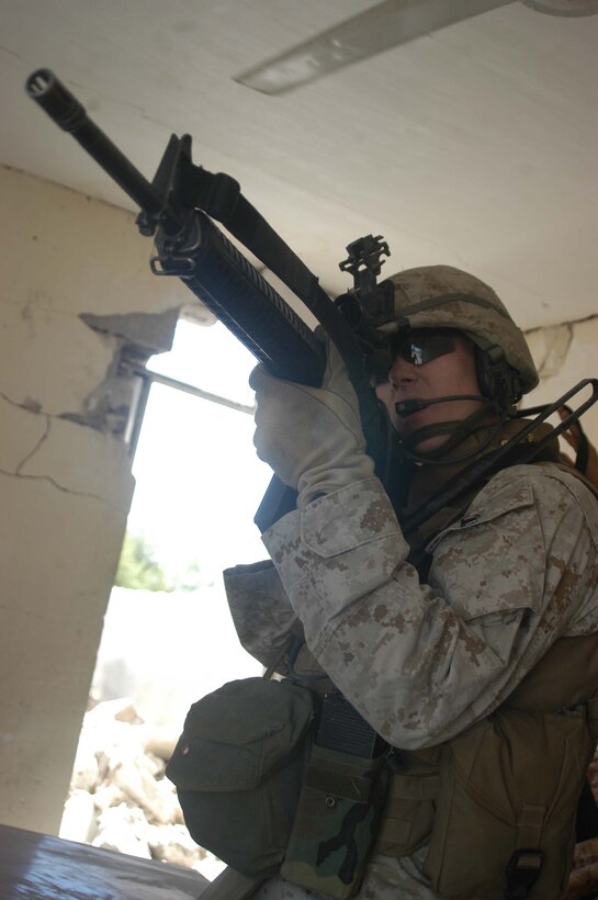AR RAMADI, IRAQ (May 10, 2005) -Wielding his M-16, 1st Lt. Latham E. Fell, the executive officer for Company C, 1st Battalion, 5th Marine Regiment, provides security for Marines with Team 1, Detachment 3, 5th Civil Affairs Group, while they inspect minor property damage done to two businesses in the city here. Civil affairs Marines conducted a detailed battle site assessment of two automotive shops that elements of 1st Battalion, 5th Marines, damaged during a recent cordon and search mission. Marines with 5th CAG will ensure the owners are properly compensated for the damages incurred to their establishments. Photo by Cpl. Tom Sloan