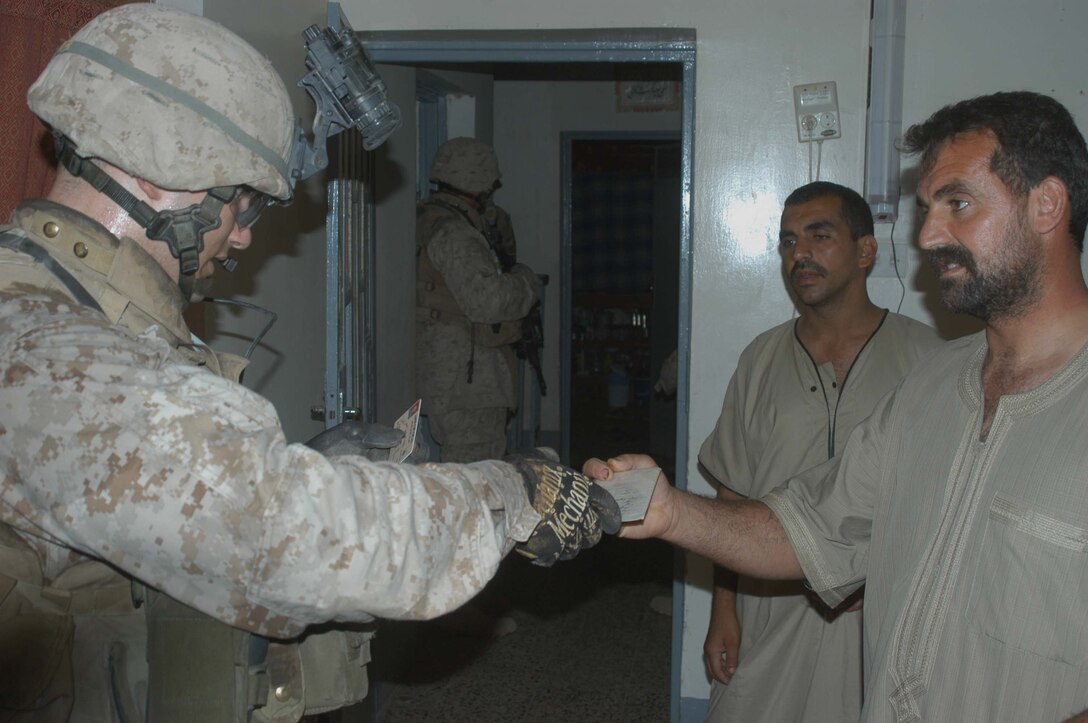 AR RAMADI Iraq (July 10, 2005) - Corporal Michael T. Wheat, a mortar man with 4th Platoon, Company W, 1st Battalion, 5th Marine Regiment, checks an Iraqi man's identification card during a mission in the city here early July 10. The 21-year-old from Merkel, Texas, and fellow Marines with 3rd and 4th Platoon conducted a raid between 1 a.m. and 3 a.m., during which time they captured an insurgent responsible for launching small arms and improvised explosive device(IED) attacks on coalition forces. Photo by: Cpl. Tom Sloan