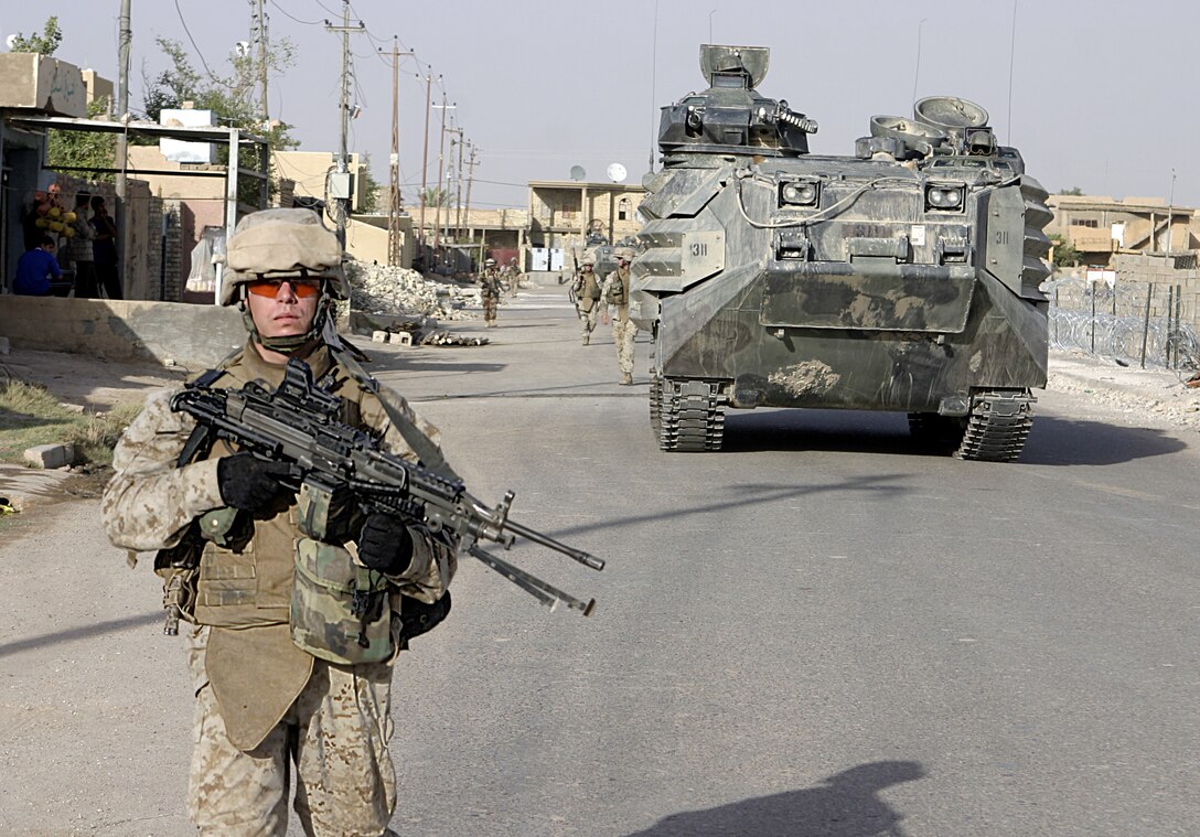 FALLUJAH, Iraq - Lance Cpl. Benjamin Pellum, a squad automatic weapon gunner with 4th Platoon, Company B, 1st Battalion, 6th Marine Regiment, provides security along a street here July 10 during Operation Rolling Barrage.  The 23-year-old Chesterfield, Va. native worked alongside fellow infantrymen, mechanized units and Iraqi Security Forces to block off and search neighborhoods throughout the city for weapons, explosives and insurgent activity.