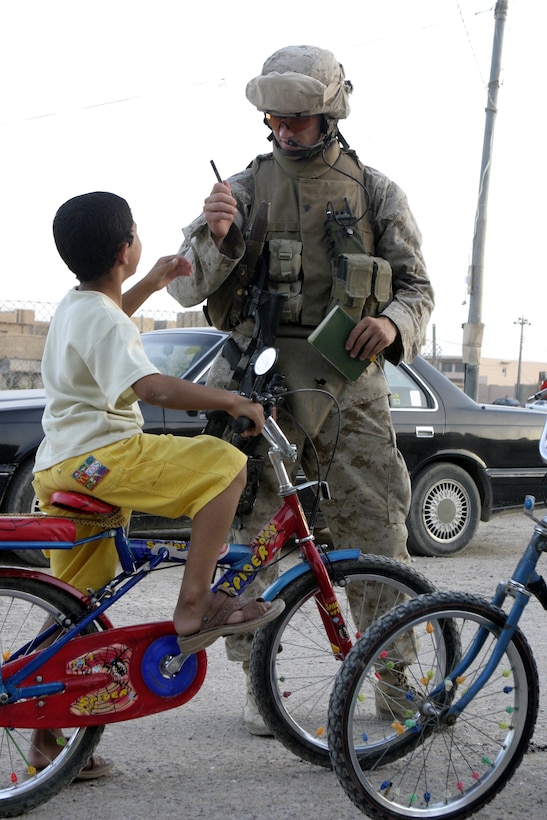 FALLUJAH, Iraq - Cpl. Adam Meier, a squad leader with 4th Platoon, Company B, 1st Battalion, 6th Marine Regiment, hands an Iraqi child on the street a pen here July 10 while conducting Operation Rolling Barrage.  Meier worked alongside fellow infantrymen, mechanized units and Iraqi Security Forces to block off and search neighborhoods throughout the city for weapons, explosives and insurgent activity.