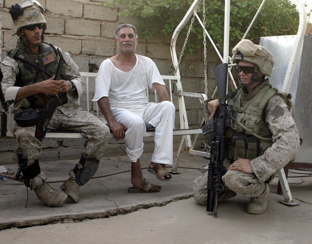 FALLUJAH, Iraq - Lance Cpl. Jonathan Blinn, an infantryman with 4th Platoon, Company B, 1st Battalion, 6th Marine Regiment, left, an Iraqi citizen, and an interpreter, Coco, stop to speak outside a residency here July 10 during Operation Rolling Barrage.  Blinn worked alongside fellow infantrymen, mechanized units and Iraqi Security Forces to block off and search neighborhoods throughout the city for weapons, explosives and insurgent activity.