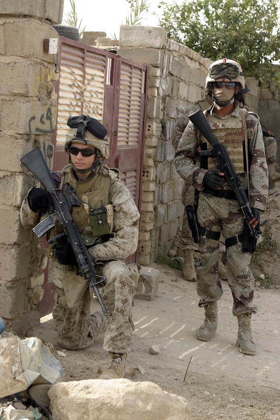 FALLUJAH, Iraq - A Marine with 4th Platoon, Company B, 1st Battalion, 6th Marine Regiment and an Iraqi soldier pause along a street corner here July 10 to provide security during Operation Rolling Barrage.  Company B personnel worked alongside fellow infantrymen, mechanized units and Iraqi Security Forces to block off and search neighborhoods throughout the city for weapons, explosives and insurgent activity.