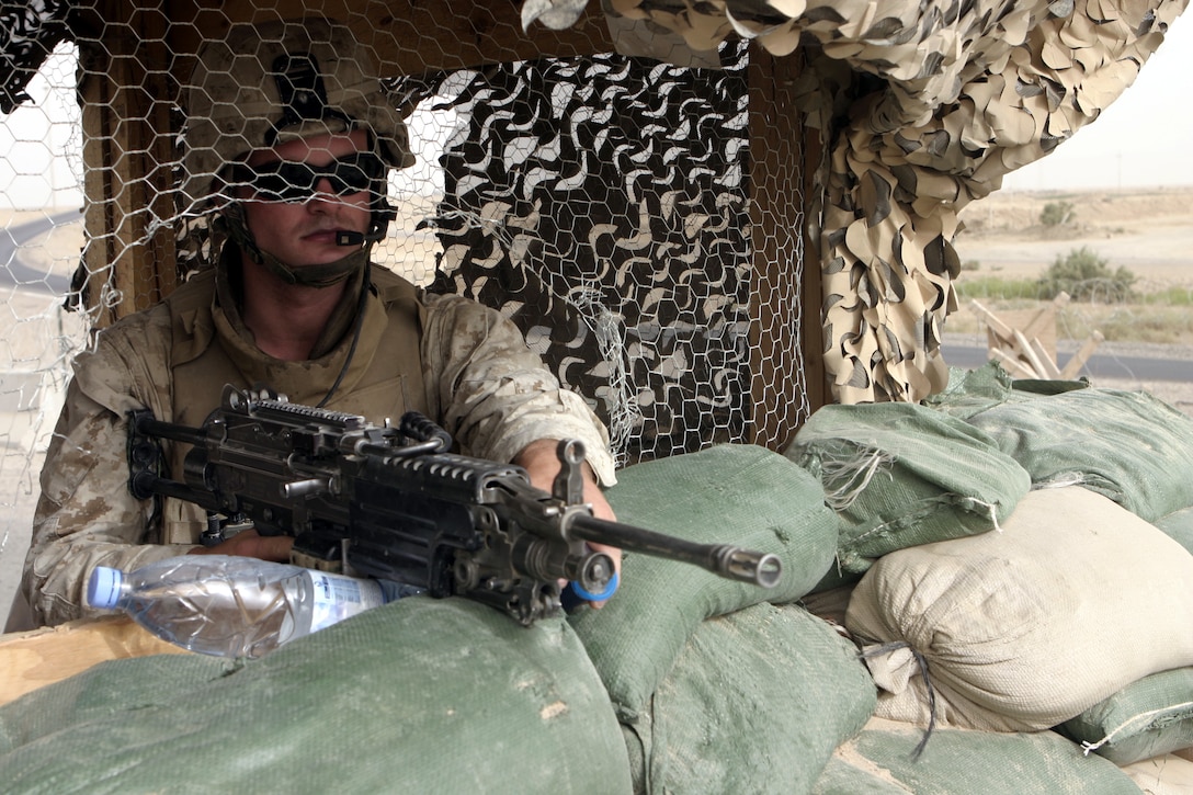 FALLUJAH, Iraq - Lance Cpl. Daniel Muller, an infantryman with 1st Battalion, 6th Marine Regiment, stands behind his M249 Squad Automatic Weapon inside a post at Entry Control Point-One here Aug. 10 as he provides area security.  Marines with 1st Battalion, 6th Marine Regiment oversee Iraqi policemen with the Public Order Brigade as they search the thousands of automobiles and local citizens entering the city every day for weapons and contraband.