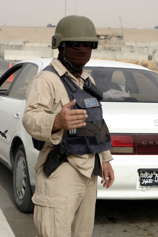 FALLUJAH, Iraq - An Iraqi policeman waves vehicles through Fallujah's Entry Control Point-One Aug. 10.  Marines with 1st Battalion, 6th Marine Regiment oversee Iraqi policemen with the Public Order Brigade as they search the thousands of automobiles and local citizens entering the city every day for weapons and contraband.