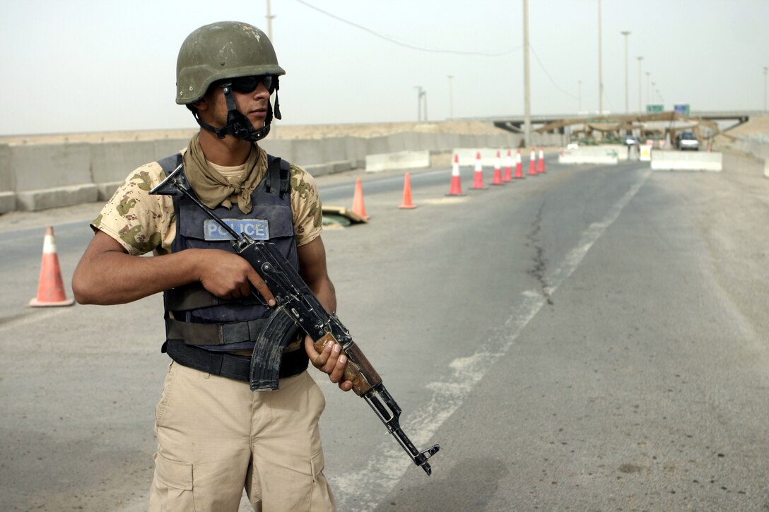 FALLUJAH, Iraq - An Iraqi policeman provides security aboard Fallujah's Entry Control Point-One Aug. 10.  Marines with 1st Battalion, 6th Marine Regiment oversee Iraqi policemen with the Public Order Brigade as they search the thousands of automobiles and local citizens entering the city every day for weapons and contraband.
