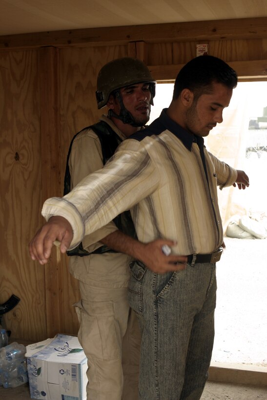 FALLUJAH, Iraq - An Iraqi policeman pats down a resident aboard Fallujah's Entry Control Point-One Aug. 10.  Marines with 1st Battalion, 6th Marine Regiment oversee Iraqi policemen with the Public Order Brigade as they search the thousands of automobiles and local citizens entering the city every day for weapons and contraband.