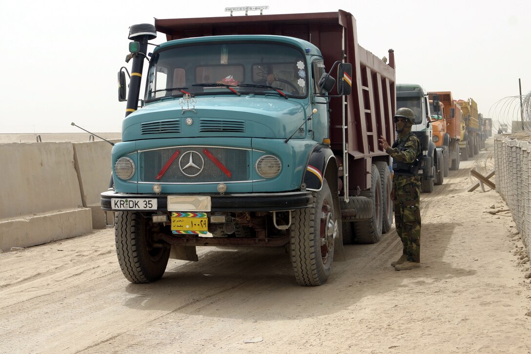 FALLUJAH, Iraq - An Iraqi policeman directs heavy truck traffic aboard Fallujah's Entry Control Point-One "Alpha" Aug. 10.  Marines with 1st Battalion, 6th Marine Regiment oversee Iraqi policemen with the Public Order Brigade as they search the thousands of automobiles and local citizens entering the city every day for weapons and contraband.