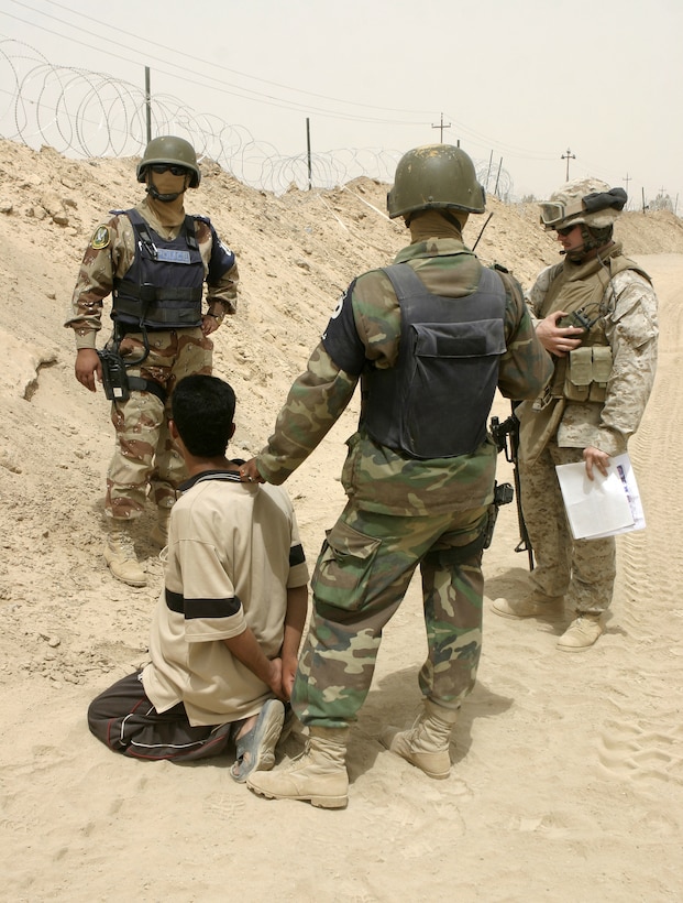 FALLUJAH, Iraq - Cpl. Jason T. Johnson, a sergeant of the guard at 1st Battalion, 6th Marine Regiment's Entry Control Point-One "Alpha," and Iraqi policemen with the Public Order Brigade guard an insurgent they detained here Aug. 10 for weapons possession.  Iraqi Security Forces and U.S Marines apprehended a total of four suspected terrorists for weapons possession, emplacing roadside bombs, and possible involvement in a nearby firefight.