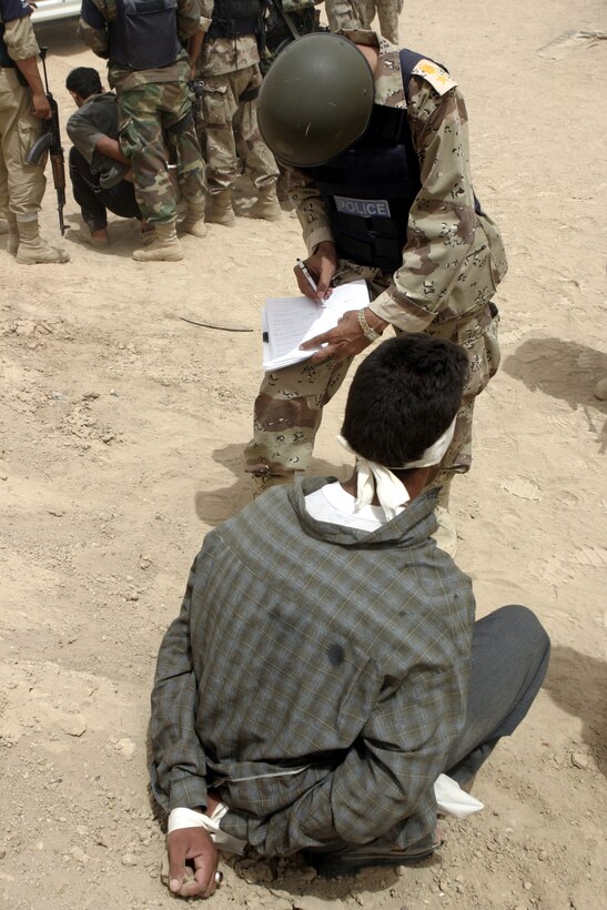 FALLUJAH, Iraq - An Iraqi policeman with the Public Order Battalion jots down information on an insurgent they apprehended here Aug. 10.  Iraqi Security Forces and Marines with 1st Battalion, 6th Marine Regiment apprehended a total of four suspected terrorists for weapons possession, emplacing roadside bombs, and possible involvement in a nearby firefight.