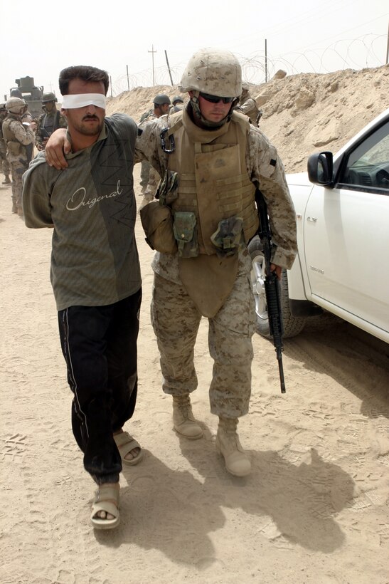 FALLUJAH, Iraq - Cpl. Timothy Culbertson, a Marine manning the city's Entry Control Point-One "Alpha," escorts an insurgent Iraqi policemen with the Public Order Brigade apprehended here Aug. 10.  Iraqi Security Forces and Marines with 1st Battalion, 6th Marine Regiment apprehended a total of four suspected terrorists for weapons possession, emplacing roadside bombs, and possible involvement in a nearby firefight.