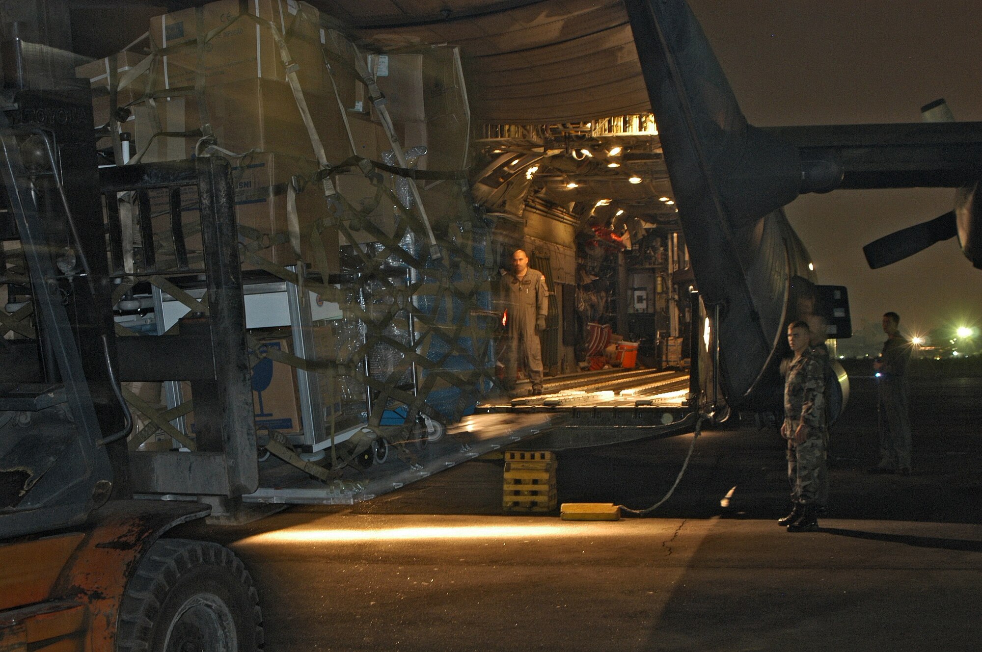 MEDAN, Indonesia -- A loadmaster guides a forklift into position here during a load of humanitarian supplies.  The aircraft made two deliveries into the tsunami-battered region of Banda Aceh on Jan. 8.  Another MC-130H Combat Talon II crew from the 353rd Special Operations group made two additional deliveries.  (U.S. Air Force photo by Master Sgt. Michael Farris)
