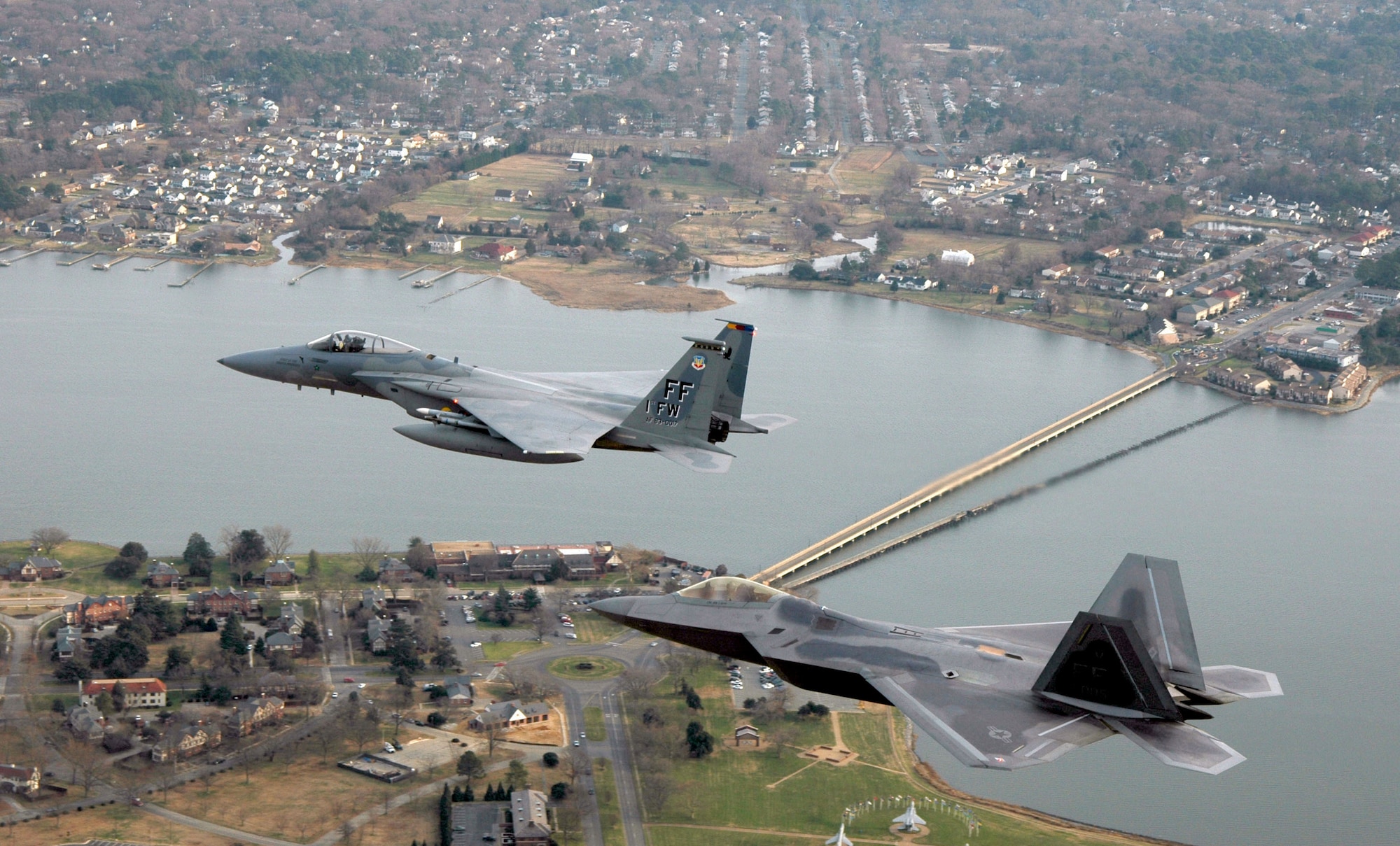 LANGLEY AIR FORCE BASE, Va. -- An F/A-22 Raptor (foreground) and an F-15 Eagle fly over Langley Air Force Base, Va., Jan. 7.  It was the Raptor's final flight before landing at its new home here.  The F/A-22 will be used as a training tool to keep 1st Fighter Wing maintainers proficient on the Raptor.  The wing's 27th Fighter Squadron pilots will begin flying operational missions later this month when the second Raptor arrives.  (Air Force photo by Senior Master Sgt. Keith Reed)