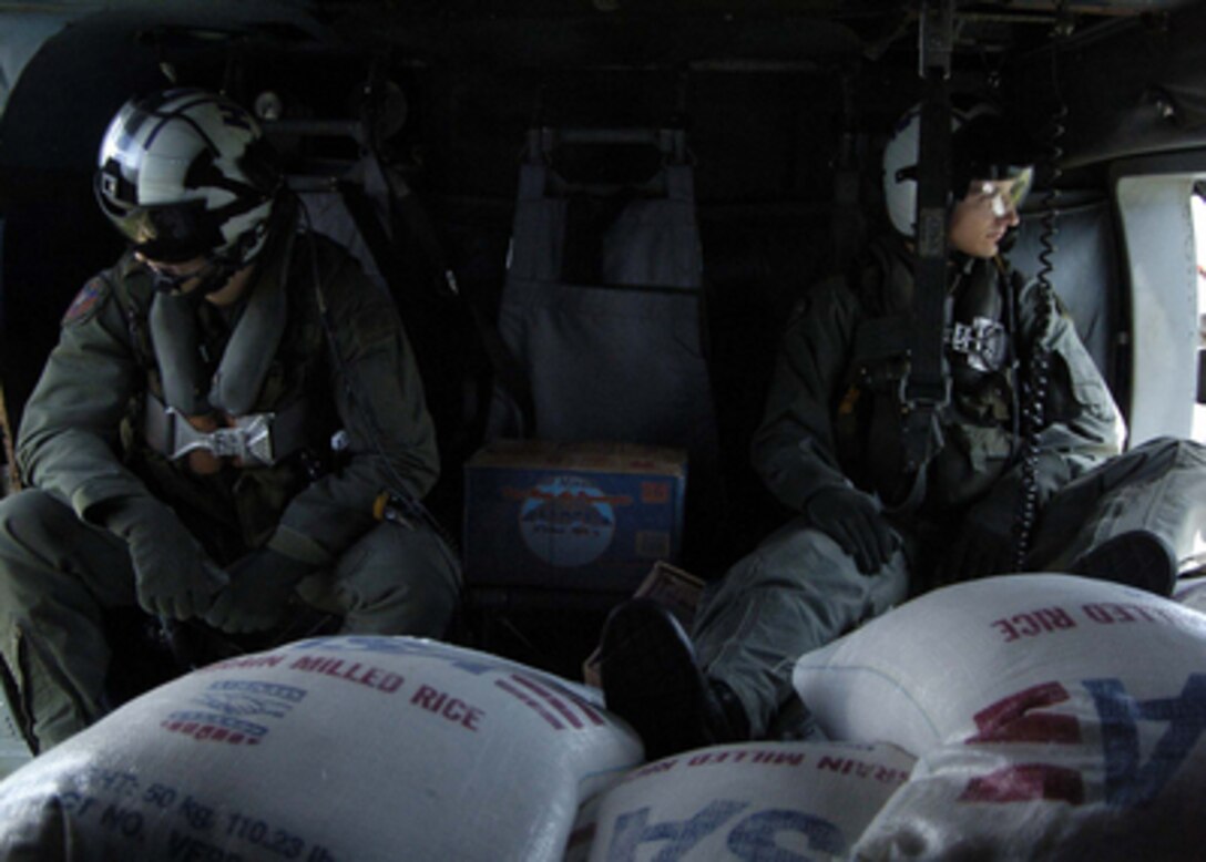 U.S. Navy Petty Officers 2nd Class Dave Matthews and Justin Garrett sit behind bags of rice in an SH-60F Seahawk helicopter en route to tsunami victims on the island of Banda Aceh, Sumatra, Indonesia, on Jan. 7, 2005. The USS Abraham Lincoln (CVN 72) and its embarked Carrier Air Wing 2 are operating in the Indian Ocean off the coasts of Indonesia and Thailand in support of Operation Unified Assistance. Matthews and Garrett are Navy Aviation Anti-Submarine Warfare Systems Operators from Helicopter Anti Submarine Squadron 2. 