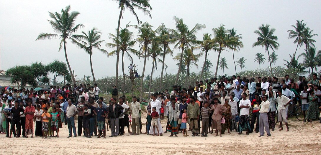 Local residents here join together on the beach to watch the Marines and Sailors of the 15th Marine Expeditionary Unit (Special Operations Capable) while they depart for USS Duluth. The 15th MEU (SOC) provided desperately needed humanitarian aid to cities and villages along Sri Lanka's southern coastline.