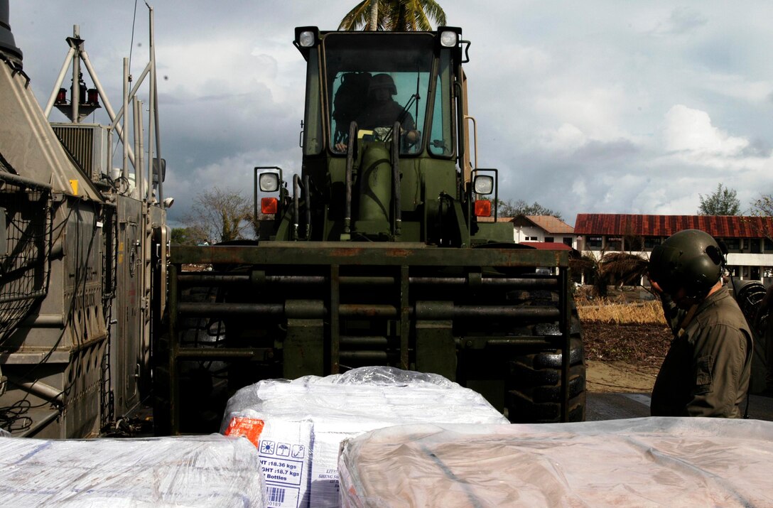 MEULABOH, Indonesia (Jan. 10, 2005) -- BM1 Patrcik Padilla, 38, a loadmaster with Beach Master Unit 1 and native of Las Cruces, N.M., direct a forklift operator as they unload humanitarian aid. The 15th Marine Expeditionary Unit (Special Operations Capable) and Amphibious Squadron 7 have been providing desperately needed humanitarian aid to cities and villages along more than 150 miles of Sumatra's western coastline.  (Photo by Gunnery Sgt. Robert Knoll)