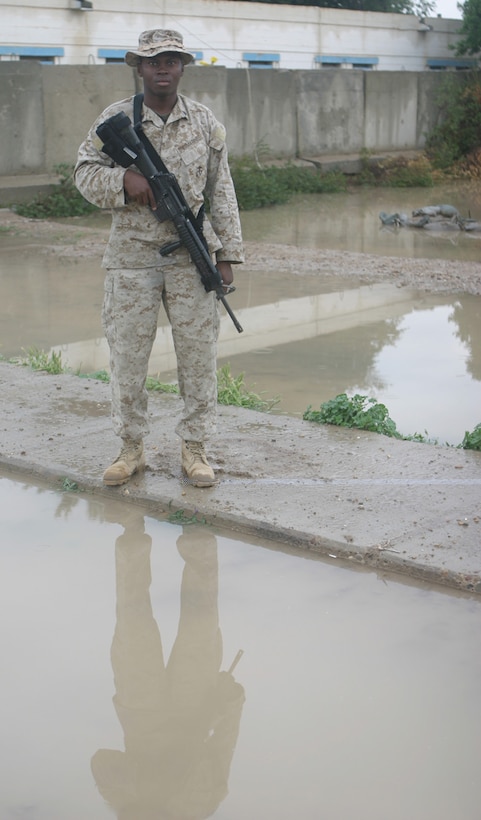 CAMP ABU GHURAYB, IRAQ – Sergeant Winston T. Daley, a Bridgeport, Conn., native, stands next to the flooded area, where one day before was dry and dusty.  Daley and his squad patrolled in Nasser Wa Saalam despite the mud and rain.  Official U.S. Marine Corps Photo by Lance Cpl. Athanasios L. Genos.