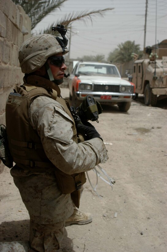 AR RAMADI Iraq (June 11, 2005) - Corporal John R. Quiroz, a machine gunner and vehicle commander for 1st Section, 5th Mobile Assault Platoon, Company W, 1st Battalion, 5th Marine Regiment, kneels down and talks to his comrades on his radio during a mission in the city here. The 24-year-old from San Antonio, Texas, and his fellow warriors conducted a presence patrol in the southern part of the city in an effort to uncover insurgent activity and deter them from operating. The platoon was engaged by an enemy sniper and hit an improvised explosive device during the operation. No one was hurt and no vehicles were damaged. Photo by: Cpl. Tom Sloan.