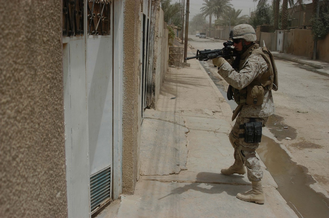 AR RAMADI Iraq (June 11, 2005) - With M-16A4 at the ready, Lance Cpl. James M. Adkins, an assault man with 1st Section, 5th Mobile Assault Platoon, Company W, 1st Battalion, 5th Marine Regiment, checks an open gate along a street here for threats during a mission in the city. The 26-year-old from Knoxville, Tenn., and his fellow warriors conducted a presence patrol in the southern part of the city in an effort to uncover insurgent activity and deter them from operating. The platoon was engaged by an enemy sniper and hit an improvised explosive device during the operation. No one was hurt and no vehicles were damaged. Photo by: Cpl. Tom Sloan.