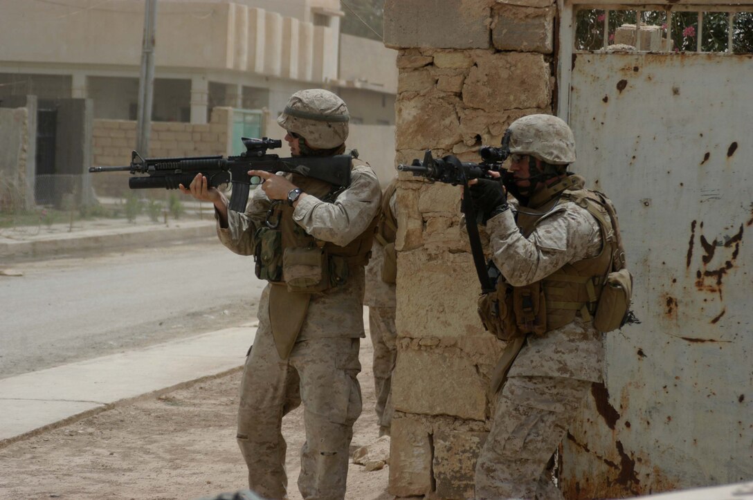 AR RAMADI Iraq (June 11, 2005) - Lance Cpl. Joe P. Lariccia(left) and 1st Lt. Adam W. Burch, both with 5th Mobile Assault Platoon, Company W, 1st Battalion, 5th Marine Regiment, have their weapons at the ready and post security for their comrades during a mission in the city here. The platoon's warriors conducted a presence patrol in the southern part of the city in an effort to uncover insurgent activity and deter them from operating. The platoon was engaged by an enemy sniper and hit an improvised explosive device during the operation. No one was hurt and no vehicles were damaged. Photo by: Cpl. Tom Sloan.