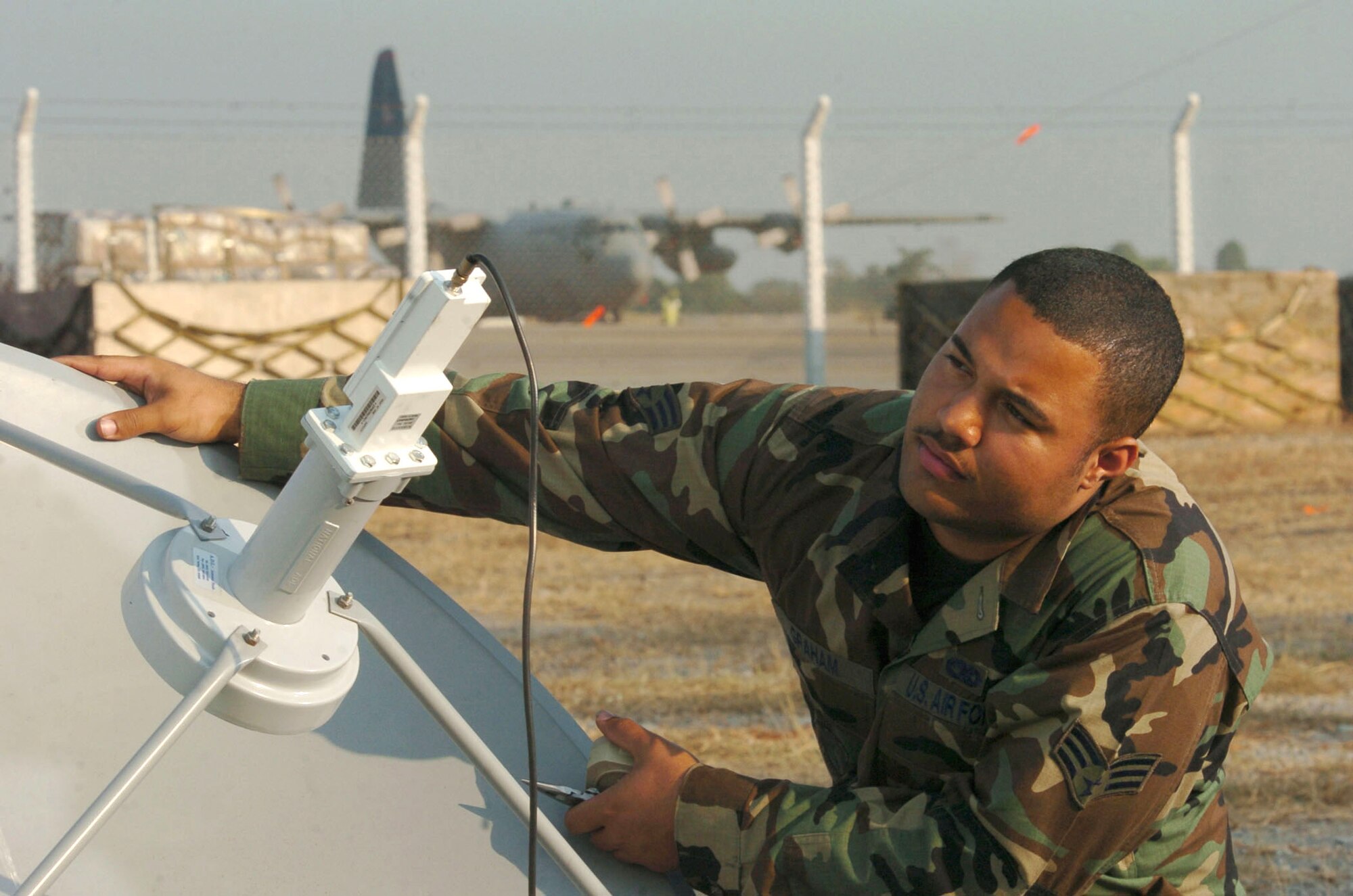 UTAPAO, Thailand -- Senior Airman John Graham inspects a satellite dish during tsunami relief operations here.  He is a technical control specialist deployed from the 18th Communications Squadron at Kadena Air Base, Japan.  The Airmen from the squadron provide communications support such as telephones and internet service to deployed troops.  (U.S. Air Force photo by Master Sgt. Val Gempis)