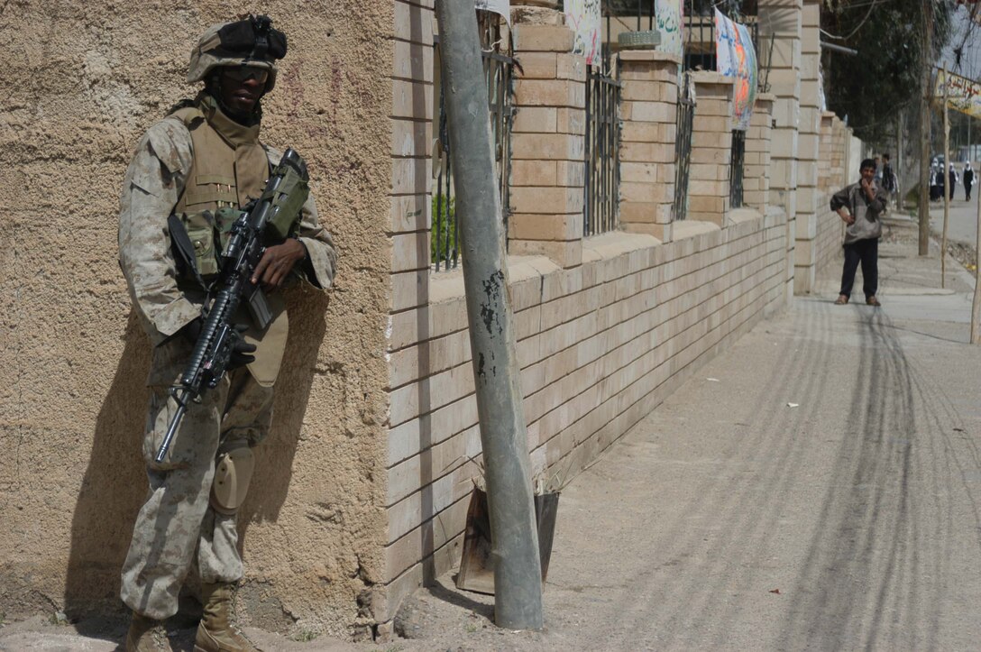 AR RAMADI, Iraq (April 11, 2005) - Lance Cpl. Dudley A. Royal, a rifleman with 2nd Squad, 1st Platoon, Company A, 1st Battalion, 5th Marine Regiment, posts security from the corner of a street during a patrol through the city here with his fellow squad members. The 21-year-old New Orleans native and his fellow leathernecks with 2nd Squad, 1st Platoon, Company A, 1st Battalion, 5th Marines, have become familiar with their area of operations where they conduct security and stability operations almost daily. They've learned to recognize landmarks to help determine what particular street they're patrolling. First Battalion, 5th Marines are two months into their seven-month deployment here in support of Operation Iraqi Freedom. Photo by Cpl. Tom Sloan
