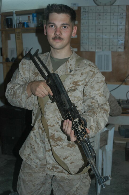 CAMP HURRICANE POINT Ar Ramadi, Iraq (May 12, 2005) - Corporal Bret J. Bell, a machine gunner with 1st Platoon, Company W, 1st Battalion, 5th Marine Regiment, holds up and AK-47 assault rifle he his fellow warriors took from insurgents during a mission in the city. The 22-year-old from Stone Mountain, Ga., and other Marines with 1st Platoon killed three insurgents while responding to a casualty evacuation request. The Marines discovered a rocket propelled grenade launcher, a PKM machine gun with more than 100 armor-piercing rounds, a Romanian assault rife, three AK-47 assault rifles and more than 300 rounds of ammunition. Photo by Cpl. Tom Sloan