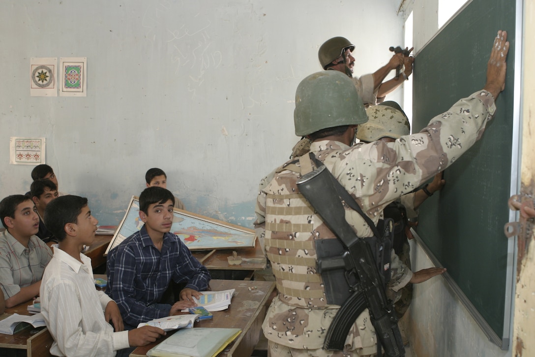 FALLUJAH, Iraq - Iraqi soldiers from the Iraqi Security Forces' 2nd Brigade visit a local school May 12 to hang up new blackboards and speak with the faculty.  The ISF personnel are currently working with Marines from 1st Battalion, 6th Marine Regiment to conduct 'Operation Blackboard,' a joint civil-military mission during which Iraqi soldiers re-supply Fallujah's schools and continue winning the citizens' trust.