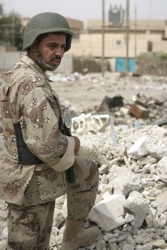 FALLUJAH, Iraq - An Iraqi soldier with the Iraqi Security Forces' 2nd Brigade looks back as he provides security outside a school here May 12, while fellow soldiers hang up new blackboards inside the classrooms.  The ISF personnel are currently working with Marines from 1st Battalion, 6th Marine Regiment to conduct 'Operation Blackboard,' a joint civil-military mission during which Iraqi soldiers re-supply Fallujah's schools and continue winning the citizens' trust.
