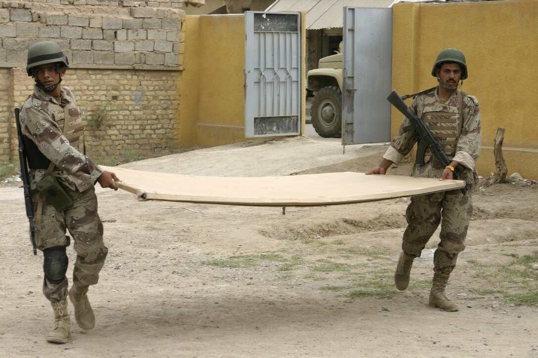 FALLUJAH, Iraq - Two Iraqi soldiers with the Iraqi Security Forces' 2nd Brigade carry a new blackboard into a school classroom here May 12.  The ISF personnel are currently working with Marines from 1st Battalion, 6th Marine Regiment to conduct 'Operation Blackboard,' a joint civil-military mission during which Iraqi soldiers re-supply Fallujah's schools and continue winning the citizens' trust.