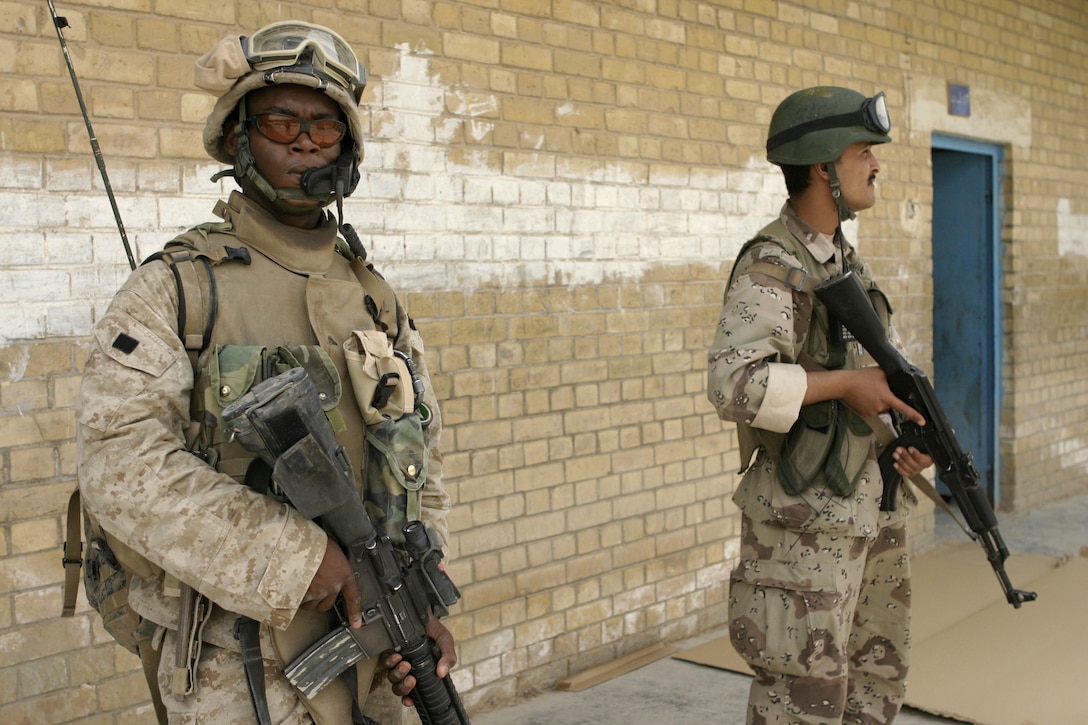 FALLUJAH, Iraq - Lance Cpl. Brandon C. Dinkins, a machine gunner with 1st Platoon, Company C, 1st Battalion, 6th Marine Regiment, provides security at a school here May 12 alongside and Iraqi soldier, while other soldiers inside a classroom hang up a new blackboard.  The 19-year-old Shreveport, La. native, his unit, and Iraqi Security Forces are currently conducting 'Operation Blackboard,' a joint civil-military mission during which Iraqi soldiers re-supply Fallujah's schools and continue winning the citizens' trust.