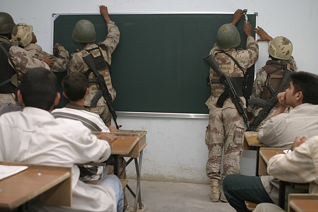 FALLUJAH, Iraq - Students at a local school observe as Iraqi soldiers hang up a new blackboard inside their classroom May 12.  Iraqi Security Forces are currently working alongside 1st Battalion, 6th Marine Regiment personnel to conduct 'Operation Blackboard,' a joint civil-military mission during which Iraqi soldiers re-supply Fallujah's schools and continue winning the citizens' trust.