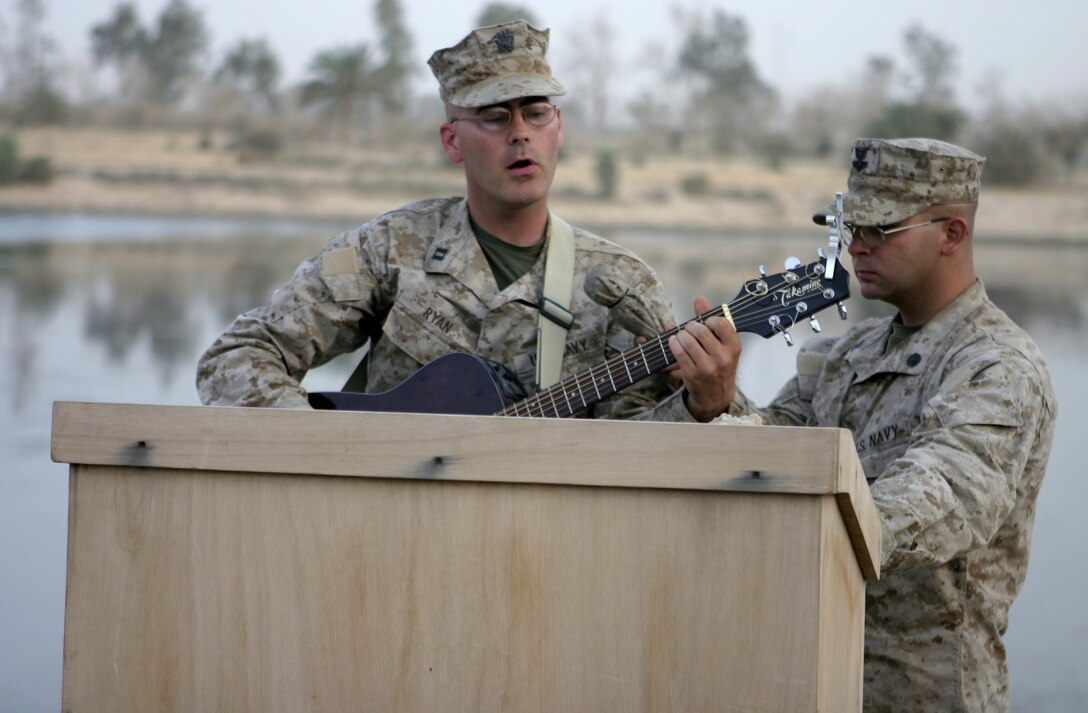 CAMP BAHARIA, Iraq - Chaplain Richard Ryan, 1st Battalion, 6th Marine Regiment's chaplain, sings a song to commemorate the lives of Lance Cpl. Mario Castillo and Lance Cpl. Andrew Kilpela during a memorial service here June 12.  The two engineers passed away June 10 when an improvised explosive device detonated near their vehicle in a roadway outside Fallujah.
