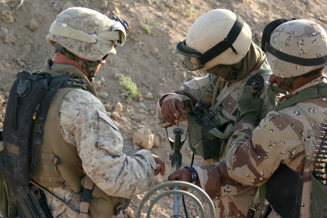 050921-M-2607O-005 CAMP FALLUJAH, Iraq - Lance Cpl. Jeremy E. Buckshot, a combat engineer attached to 2d Battalion, 2d Marine Regiment, helps an Iraqi Soldier setup the AN/PSS-12 on his gear to start his portion of the cache sweep.  The Iraqi Soldiers received classes the day before to prepare them for the cache sweep.