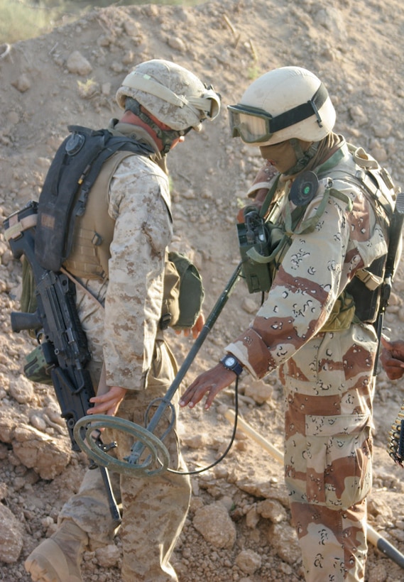 050921-M-2607O-006 CAMP FALLUJAH, Iraq - Lance Cpl. Jeremy E. Buckshot, a combat engineer attached to 2d Battalion, 2d Marine Regiment, helps an Iraqi Soldier setup the AN/PSS-12 on his gear to start his portion of the cache sweep.  The Iraqi Soldiers received classes the day before to prepare them for the cache sweep.