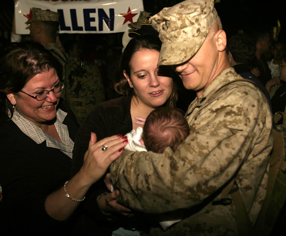 MARINE CORPS BASE CAMP LEJEUNE, N.C. - A Marine with 1st Battalion, 6th Marine Regiment cradles his baby while reuniting with loved ones after arriving here Oct. 12.  The unit returned home after conducting seven months of security and stability operations in and around Fallujah, Iraq