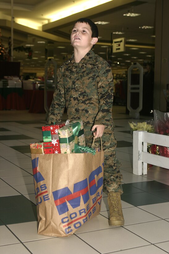 MARINE CORPS BASE CAMP LEJEUNE, N.C. - Brandon Rasnick holds presents donated outside the Marine Corps Community Services' Main Exchange here Dec. 12.  Brandon and his family visited numerous training grounds and units throughout the base while on a trip sponsored by the Make-a-Wish foundation to grant his wish of training alongside United States Marines.  Brandon is a boy from Lehigh Acres, Fla. who has cystic fibrosis, a genetic lung disorder.