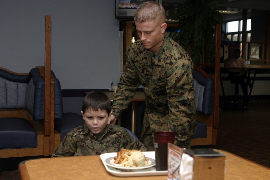 MARINE CORPS BASE CAMP LEJEUNE, N.C. - A Marine with 1st Battalion, 9th Marine Regiment helps seat six-year-old Brandon Rasnick inside a mess hall here Dec. 12.  Brandon and his family visited numerous training grounds and units throughout the base while on a trip sponsored by the Make-a-Wish foundation to grant his wish of training alongside United States Marines.  Brandon is a boy from Lehigh Acres, Fla. who has cystic fibrosis, a genetic lung disorder.
