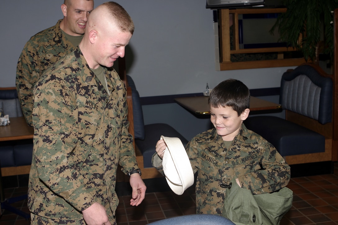 MARINE CORPS BASE CAMP LEJEUNE, N.C. - A corpsman with 1st Battalion, 9th Marine Regiment hands six-year-old Brandon Rasnick his Navy "Dixie Cup" cover after enjoying a meal with him inside a chow hall here Dec. 12.  Brandon and his family visited numerous training grounds and units throughout the base while on a trip sponsored by the Make-a-Wish foundation to grant his wish of training alongside United States Marines.  Brandon is a six-year-old boy from Lehigh Acres, Fla. who has cystic fibrosis, a genetic lung disorder.