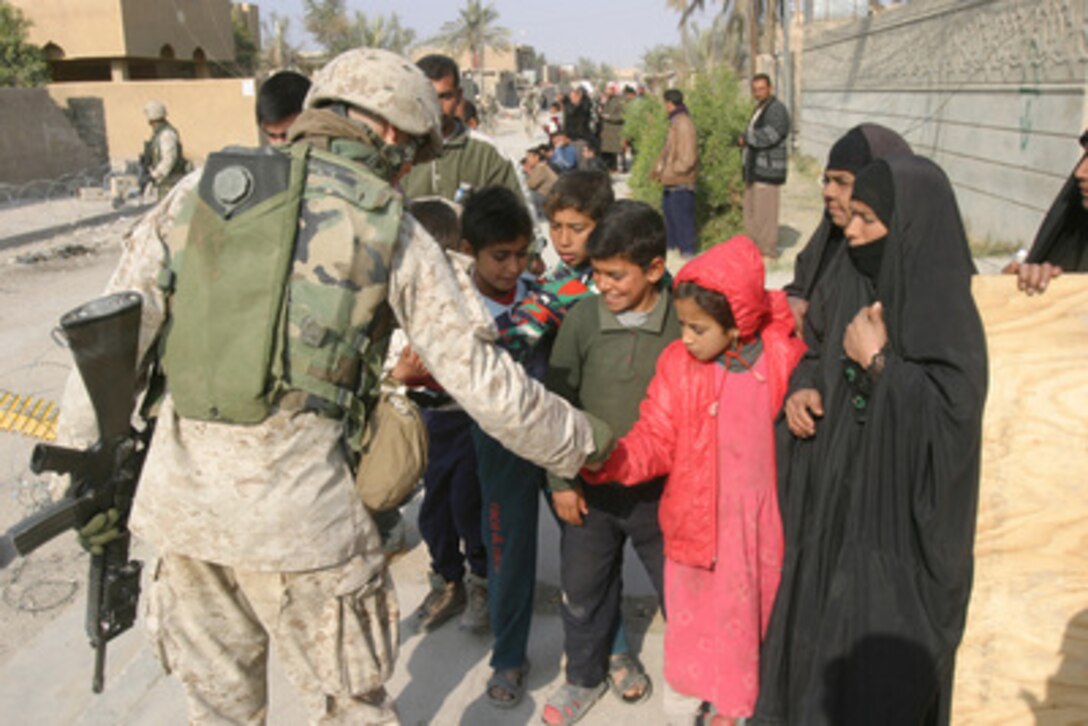Lance Cpl. Cox hands out gifts to Iraqi children during a patrol of the streets of Fallujah, Iraq, on Jan. 6, 2004. Cox is assigned to the 3rd Platoon, Lima Company, 3rd Battalion, 1st Marine Regiment, 1st Marine Division that is engaged in security and stabilization operations in the Al Anbar Province of Iraq. 