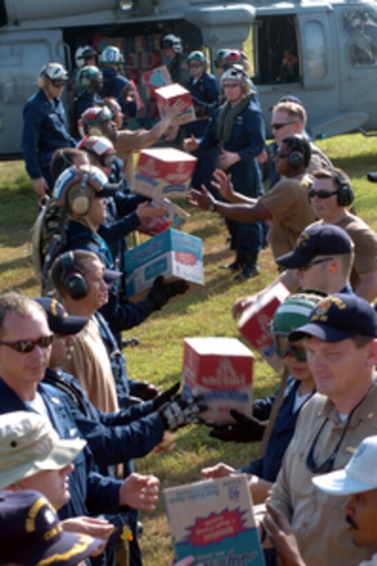 U.S. Navy sailors from the USS Abraham Lincoln (CVN 72) Carrier Strike Group and local civilians distribute food and water at Muda Air Base to disaster stricken areas of Sumatra on Jan. 9, 2005. The Lincoln Strike Group is providing sealift and airlift capabilities as well as manpower and supplies for the relief effort known as Operation Unified Assistance. 