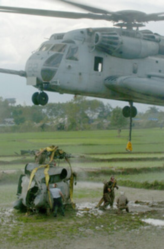 U.S. Marines prepare to attach a lift hook to a Navy SH-60 Seahawk helicopter before lifting it with a CH-53 Sea Stallion helicopter for transport on Jan. 11, 2005. The Seahawk made an emergency landing at Muda Air Base, Banda Aceh, Sumatra, on Jan. 10, 2005, while conducting relief operations. The Marines are attached to the 15th Marine Expeditionary Unit. 