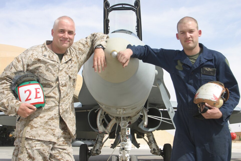 AL ASAD, Iraq ? Corporal Travis Toborg, plane captain, Marine All-Weather Fighter Attack Squadron 224 stands with his father Sgt. Timothy Toborg, electrician, Marine Fighter Attack Squadron 142 in front of a F/A-18 Hornet. Timothy rejoined the Marine Corps after a 14-year hiatus when he joined the reserves after his son joined the active duty ranks in 2002.