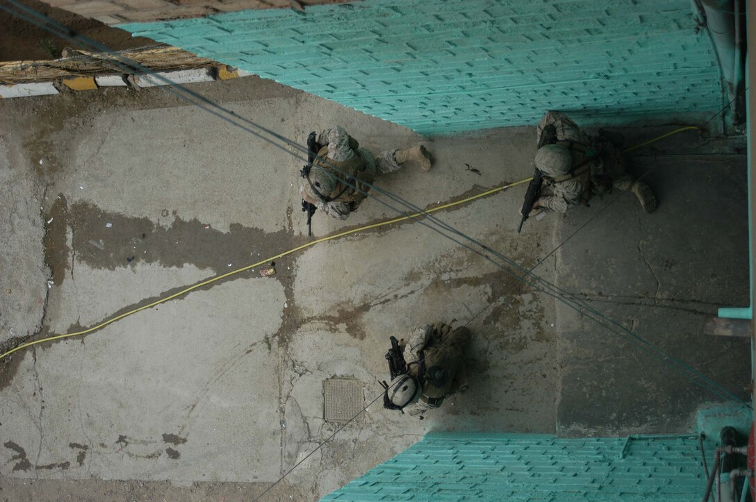 AR RAMADI, Iraq (April 9, 2005) -Three Marines with 2nd Squad, 2nd Platoon, Company C, 1st Battalion, 5th Marine Regiment, post security from the entrance of a building in a neighborhood here known as the "Ghetto" during a patrol. Patrols here often include interaction with Iraqi children. Photo by Cpl. Tom Sloan