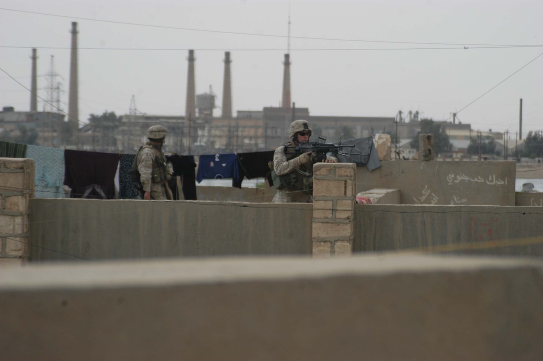 AR RAMADI, Iraq (April 9, 2005) -Two Marines with 2nd Squad, 2nd Platoon, Company C, 1st Battalion, 5th Marine Regiment, post security from the rooftop of a building in a neighborhood here known as the "Ghetto" during a patrol. Patrols here often include interaction with Iraqi children. Photo by Cpl. Tom Sloan
