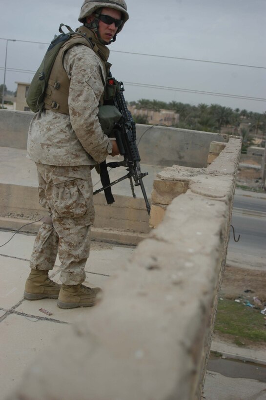 AR RAMADI, Iraq (April 9, 2005) - Lance Cpl. Donald A. Owens, a 23-year-old squad automatic weapon gunner with 2nd Squad, 2nd Platoon, Company C, 1st Battalion, 5th Marine Regiment, scans the terrain below while posting security from the rooftop of a building. The Cleburne, Texas, native and other Marines with 2nd Squad, 2nd Platoon, Company C, 1st Battalion, 5th Marines, patrolled a neighborhood here known as the "Ghetto" and handed out candy to the children and positive and anti-insurgent propaganda pamphlets to Iraqi men. Photo by Cpl. Tom Sloan