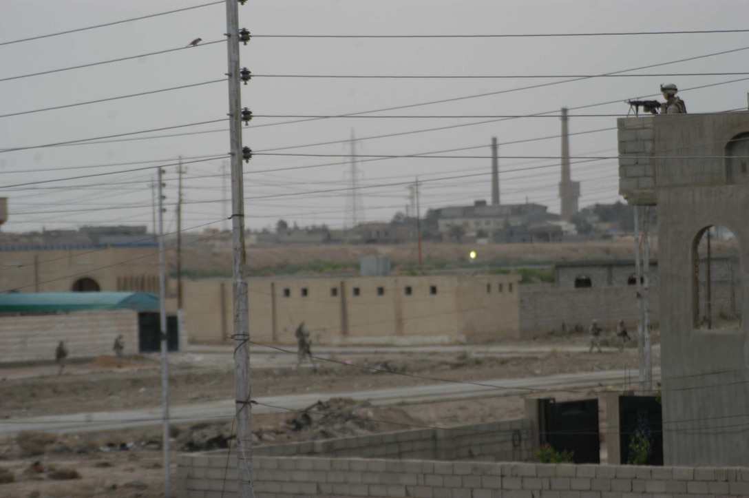 AR RAMADI, Iraq (April 9, 2005) - A Marine with 2nd Squad, 2nd Platoon, Company C, 1st Battalion, 5th Marine Regiment, posts security from the rooftop of a building while Marines patrol the streets below. Marines with 2nd Squad, 2nd Platoon, Company C, 1st Battalion, 5th Marines, patrolled a neighborhood here known as the "Ghetto" where they handed out candy to the children and positive and anti-insurgent propaganda pamphlets to Iraqi men. Photo by Cpl. Tom Sloan